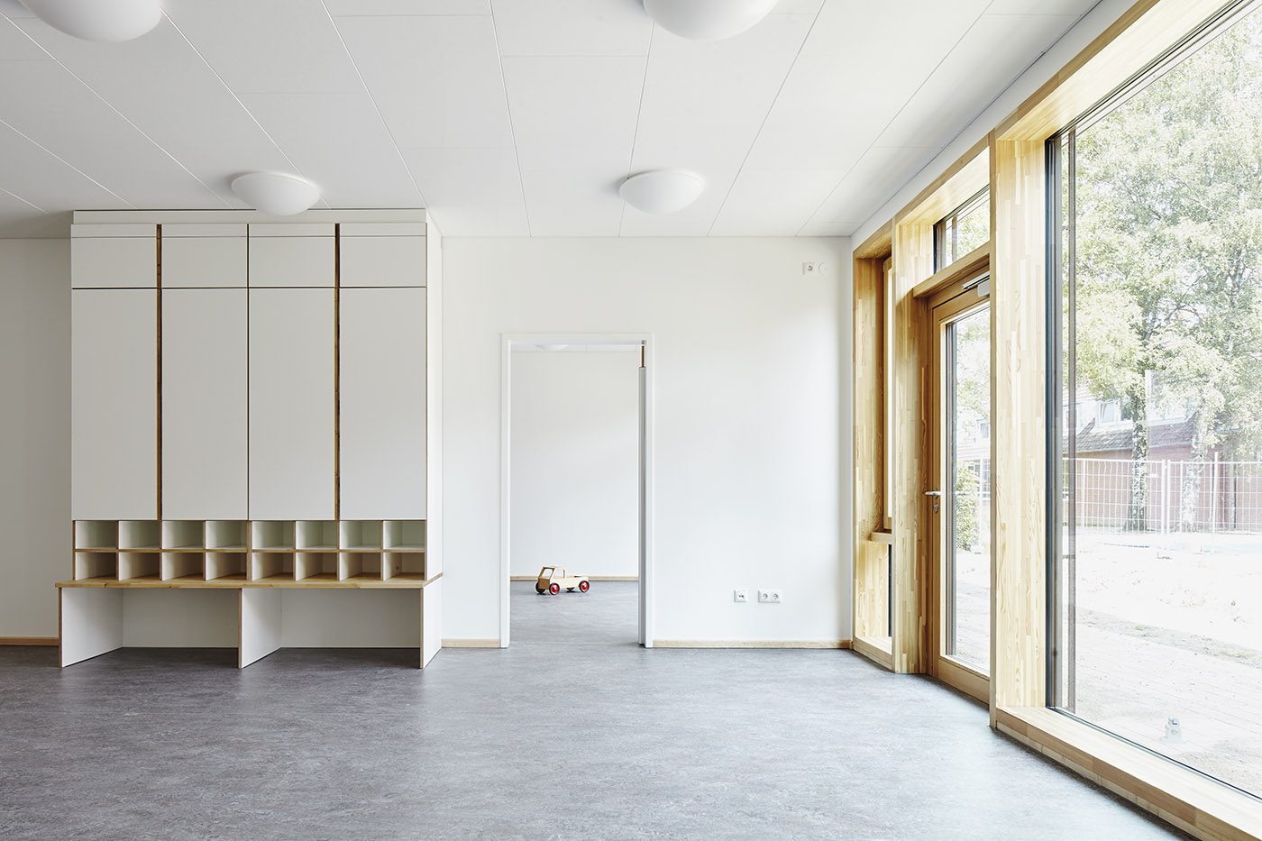 Heller Gruppenraum mit Garderobe und großen Fenstern
